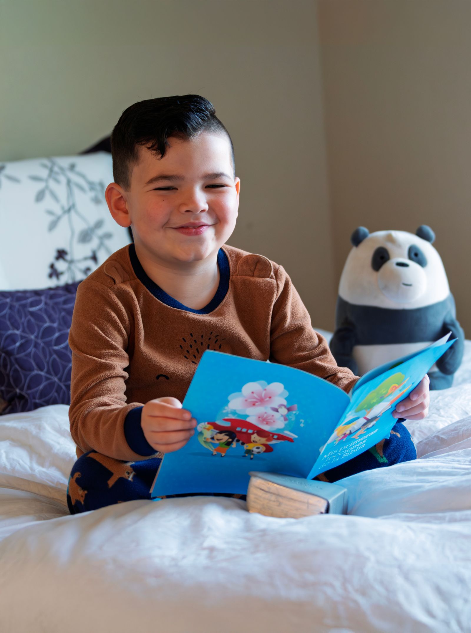 A child reading a picture book beside a favorite toy